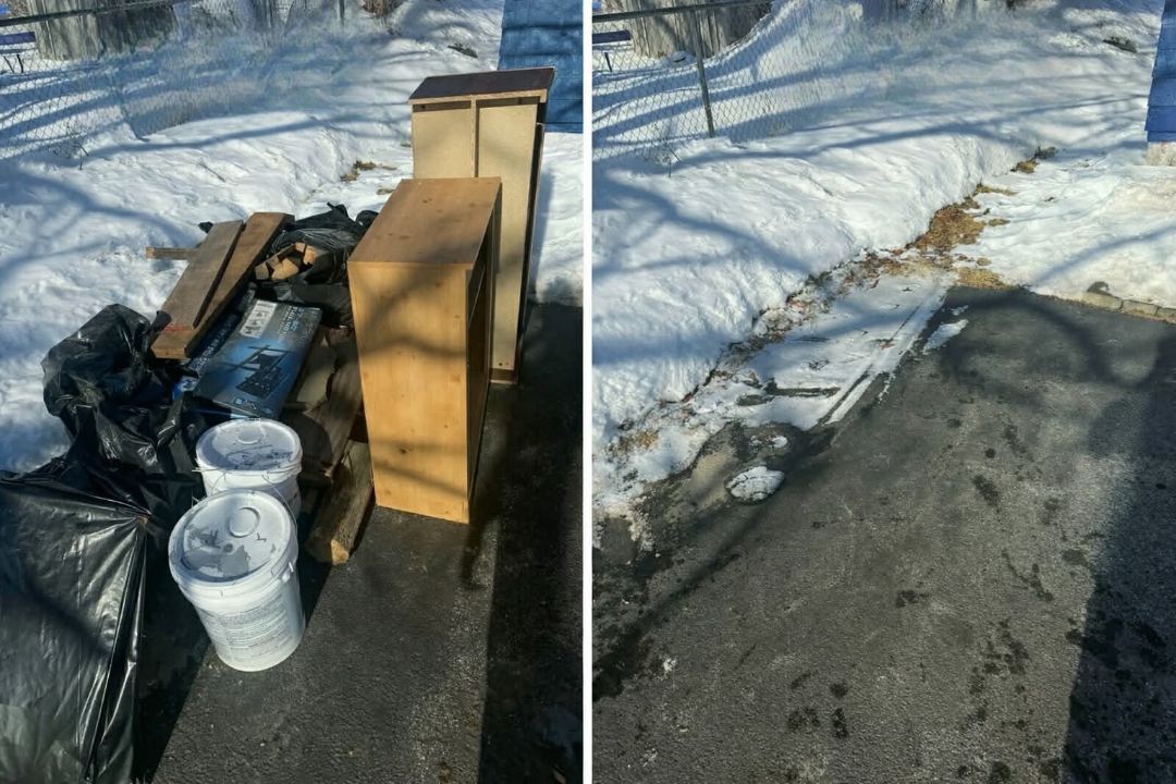 Stacked furniture and trash bins on a snowy driveway beside a cleared walkway.