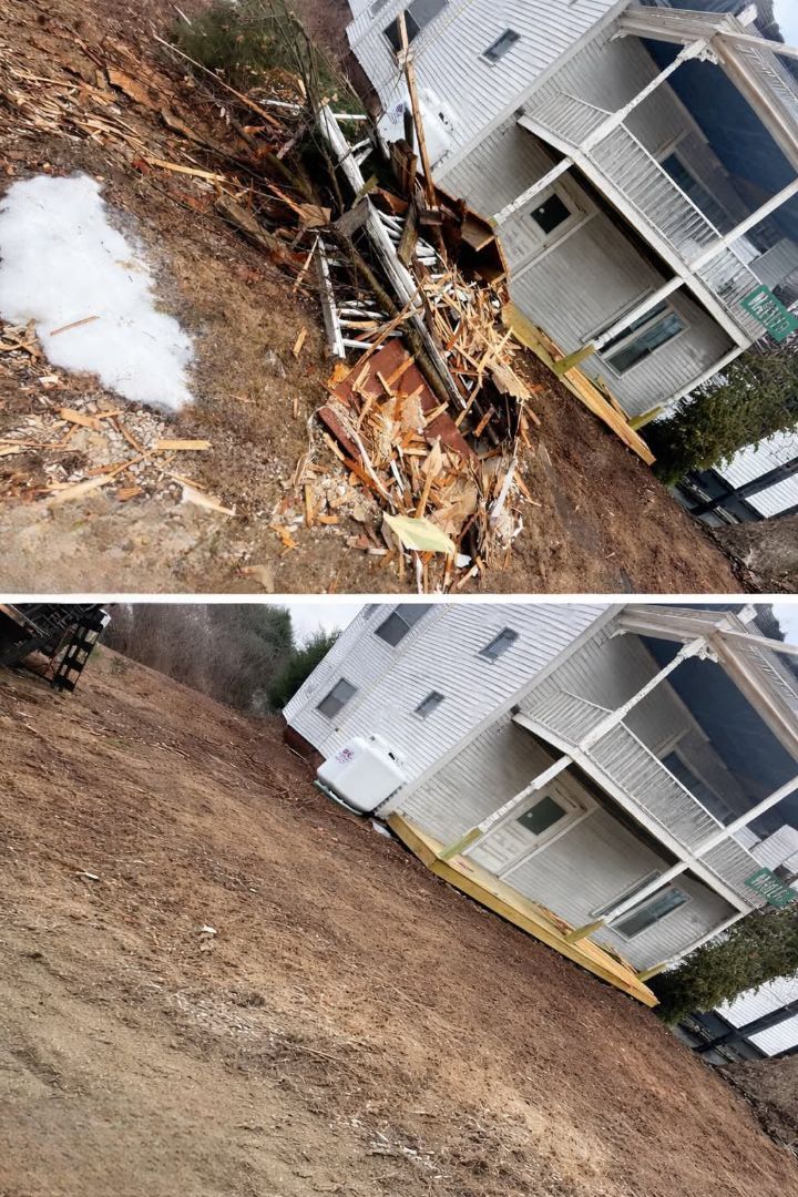 Damaged tree and debris beside a white house, with a muddy yard and patches of snow