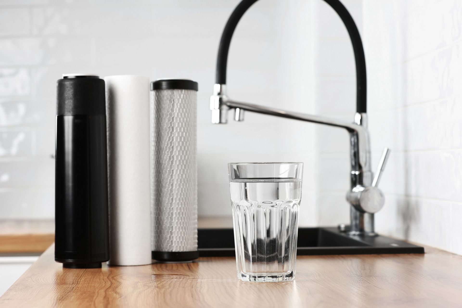 Piano di lavoro della cucina con caraffe filtranti per l'acqua e un bicchiere accanto a un rubinetto cromato.