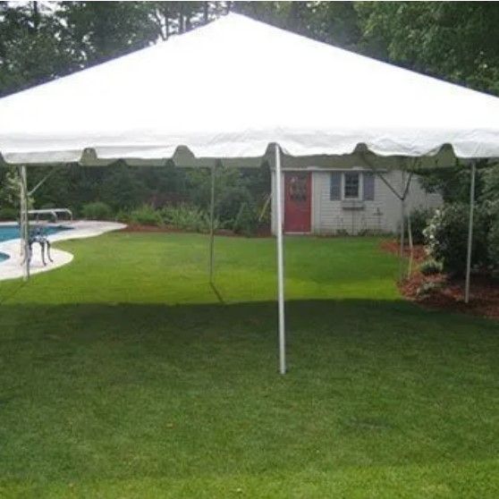 A white tent is sitting in the grass in front of a house