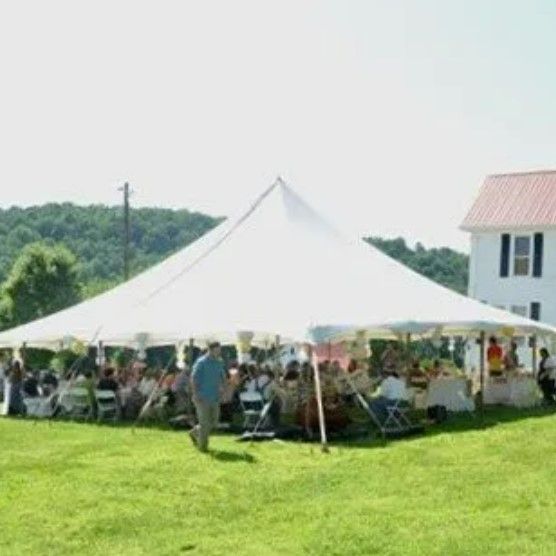 A large white tent is sitting in the middle of a grassy field.