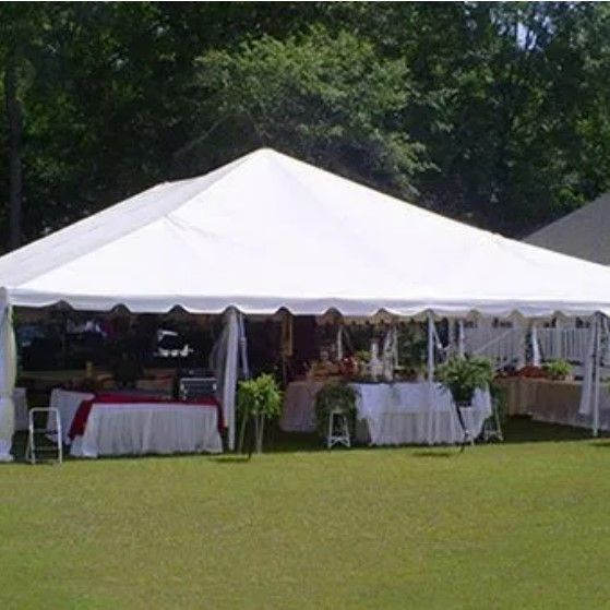 A large white tent is sitting on top of a lush green field.