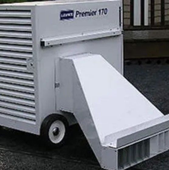 A white trailer with wheels is parked in front of a building.