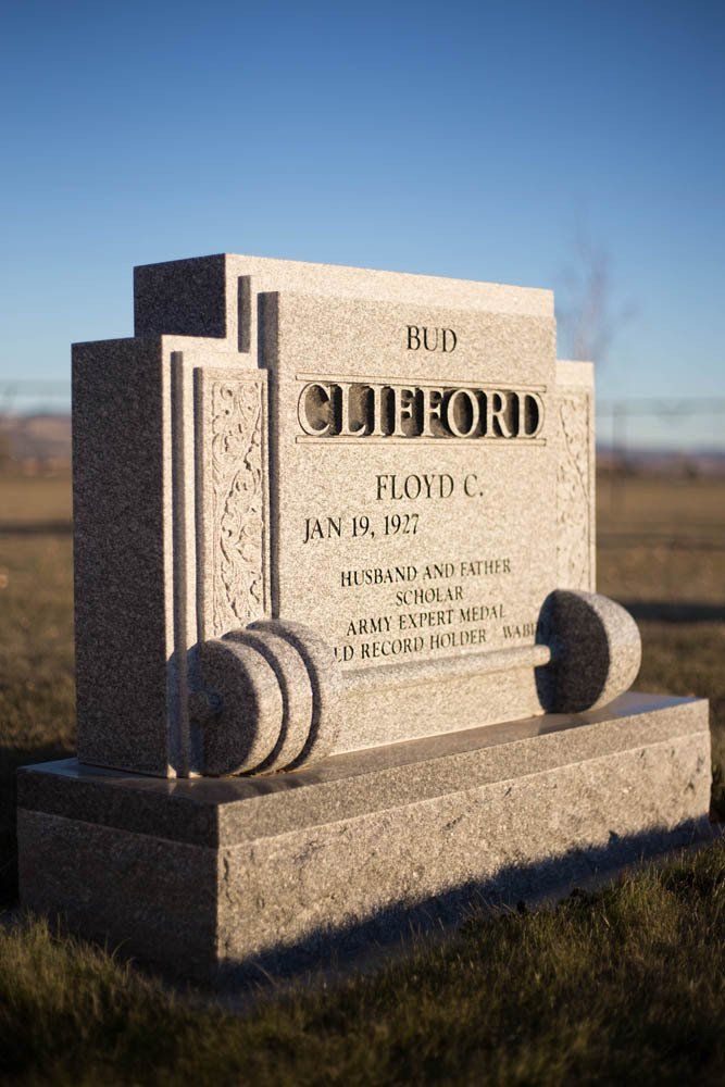 Traditional upright granite headstone for Floyd C. Clifford, engraved with a scroll design and decorative columns.