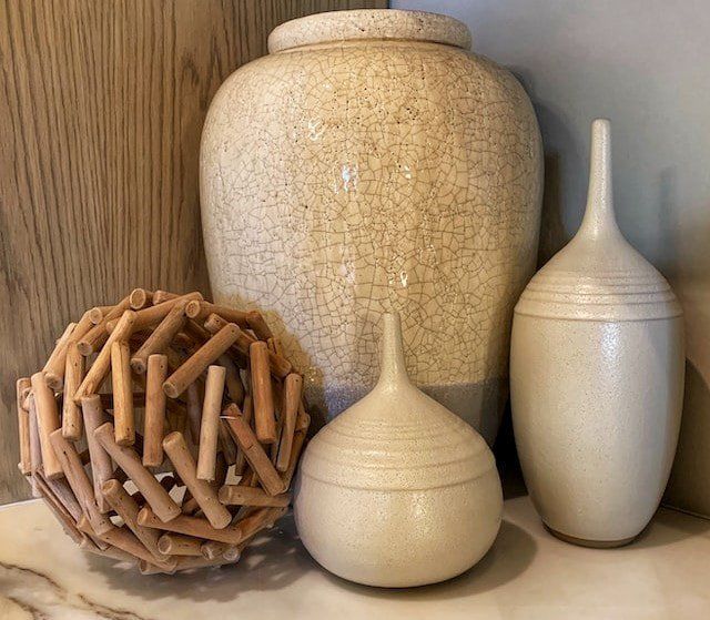 Cream-colored ceramic cremation urns displayed on a wooden shelf