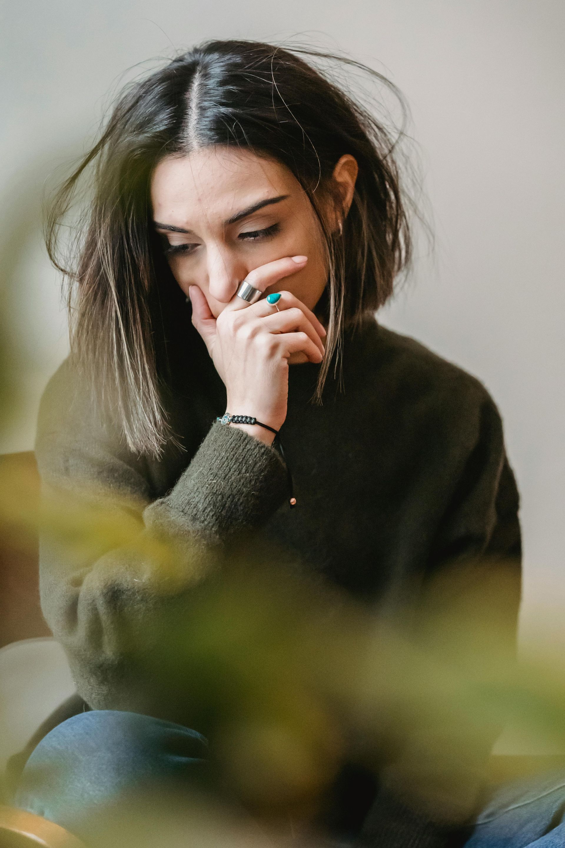 woman in a green sweater sitting down looking sad and full of grief