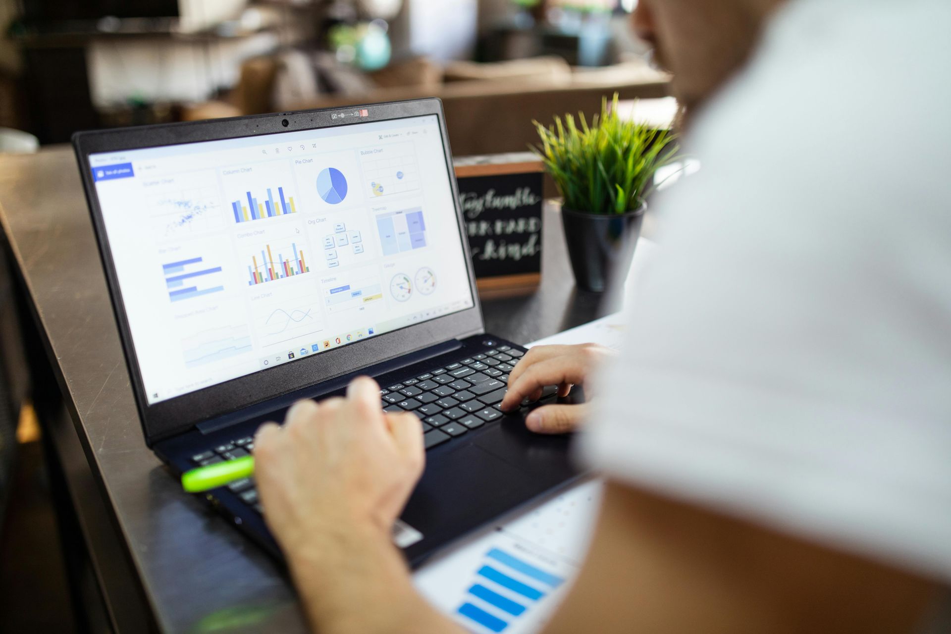Person using a laptop with analytics charts on screen in a bright office.