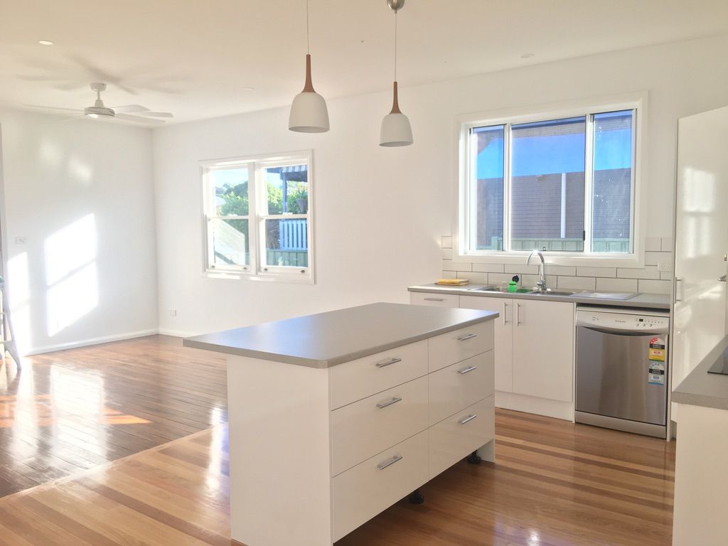 A kitchen with white cabinets and a large island in the middle.