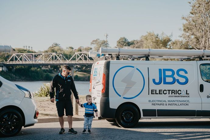 A man and a child are standing in front of a jbs electric van.