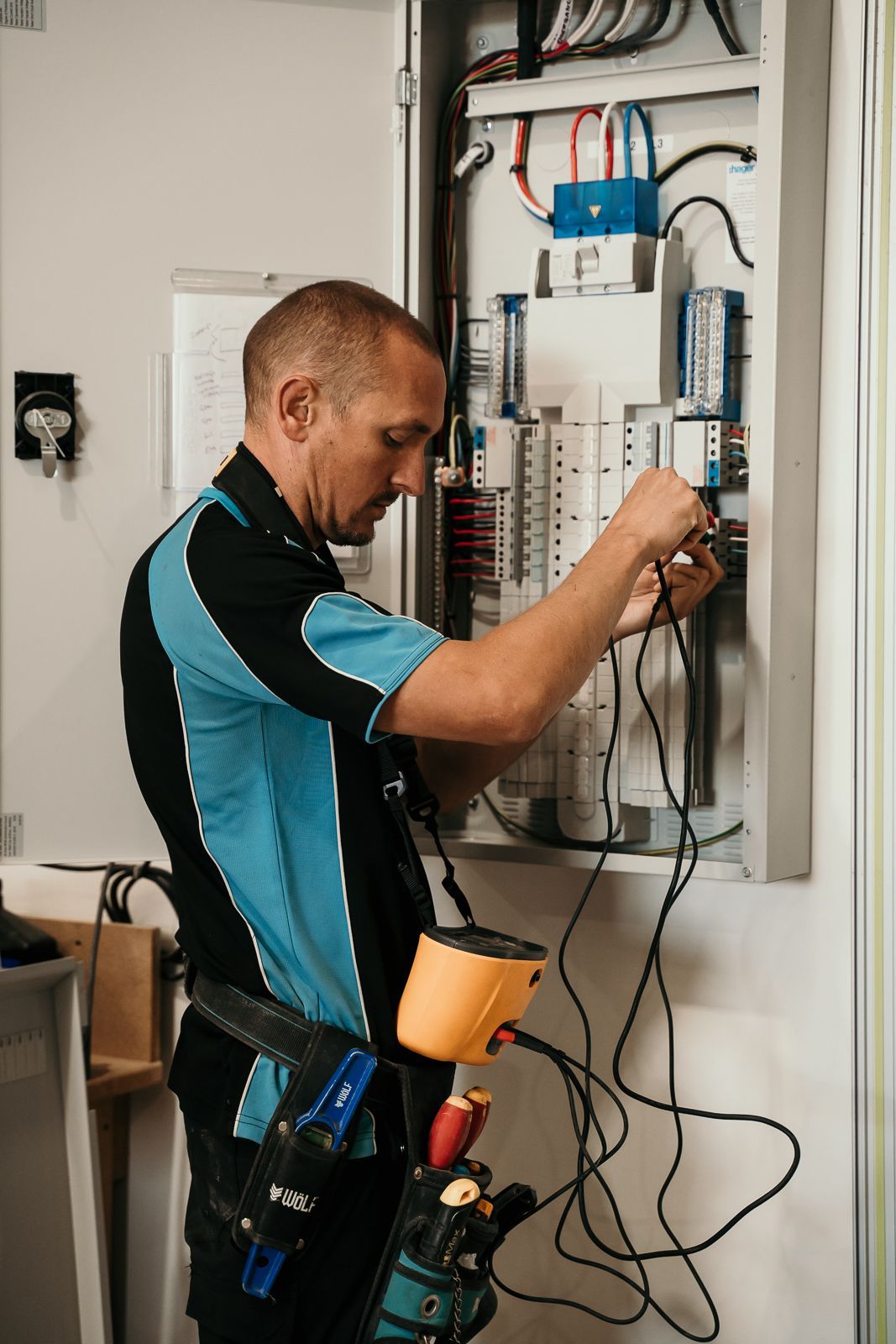 A man is working on an electrical box in a room.