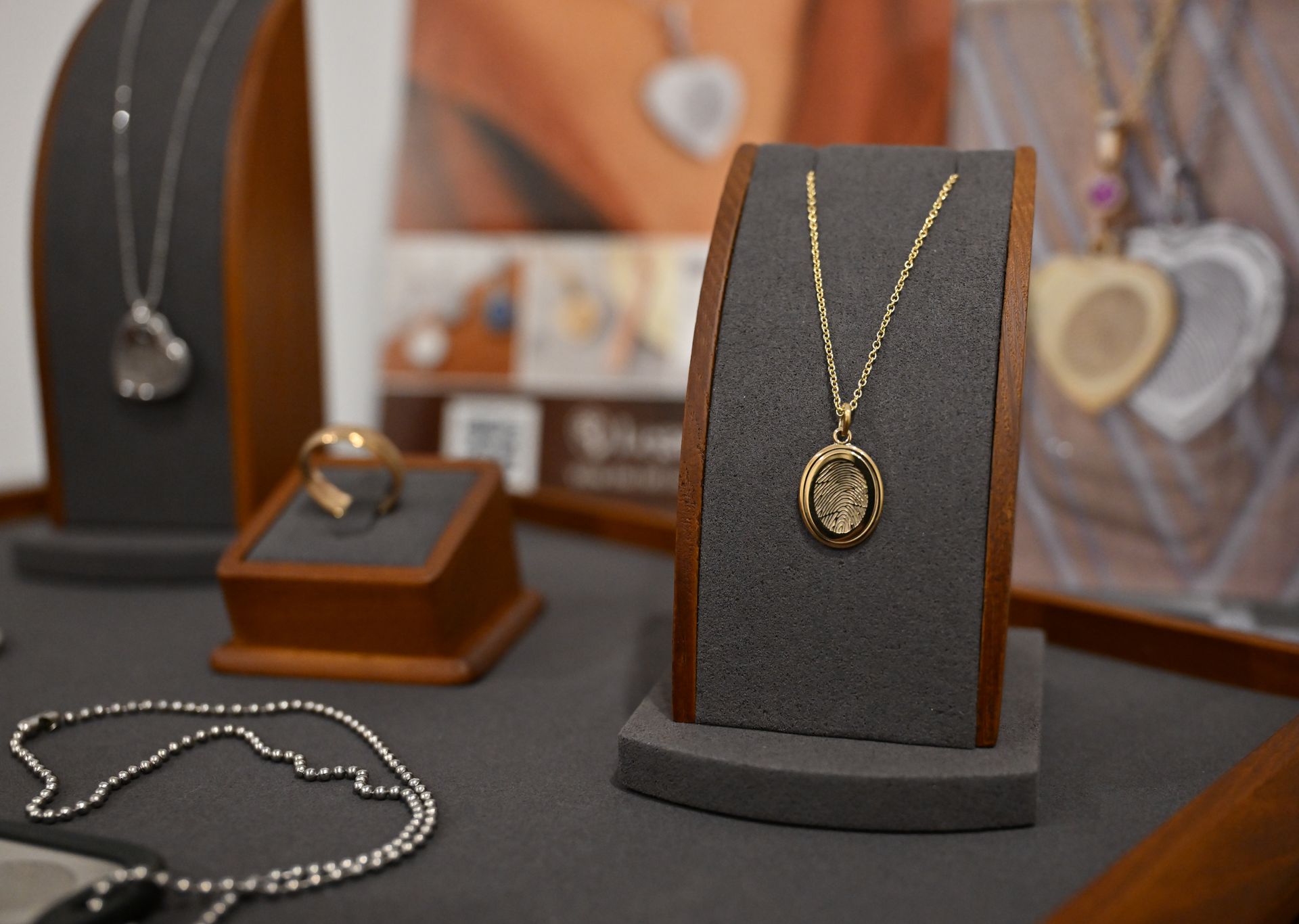 Gold jewelry display with a pendant necklace and ring on dark velvet stands in a store showcase