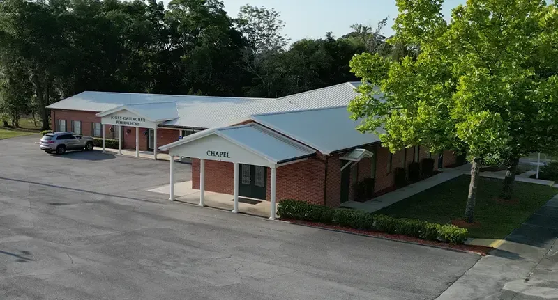Single-story brick office building with a covered entrance, parking lot, and trees surrounding it