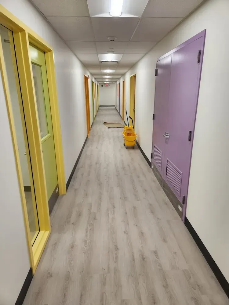 Long hallway with colorful doors and a cleaning cart.