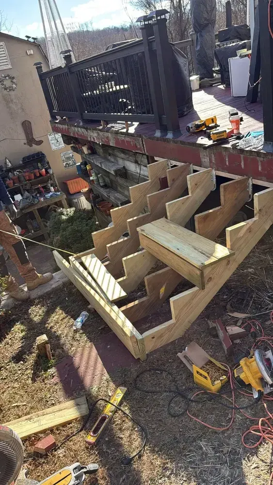 Wooden deck steps under construction outdoors, tools and materials visible.