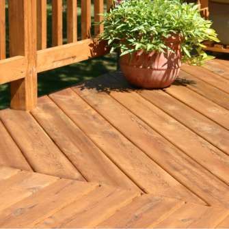 Wooden deck with a potted plant, angled planks, and a railing.
