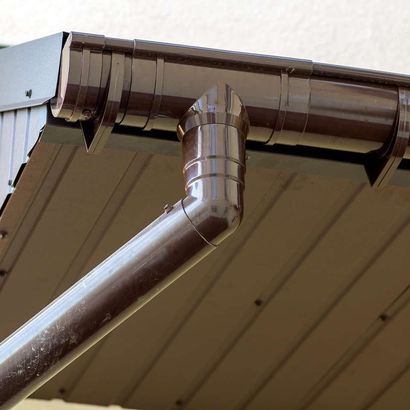 Brown gutter system on a building's roof, angled down.