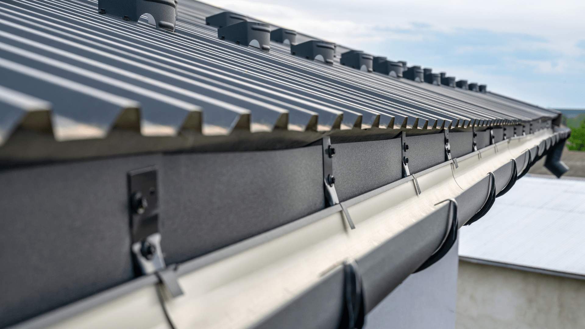 Gray roof with corrugated metal, a gutter system, and dark brackets.