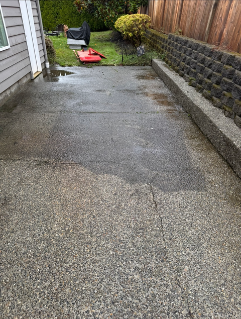 Person power washing a brick house, creating water streams.