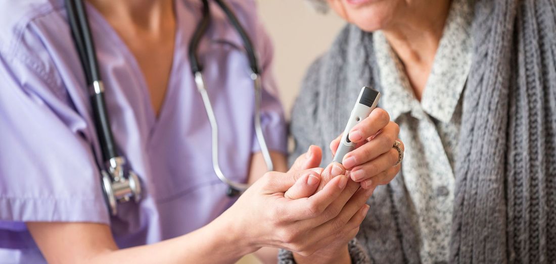Nurse checking an elderly patient’s blood sugar with a glucose meter