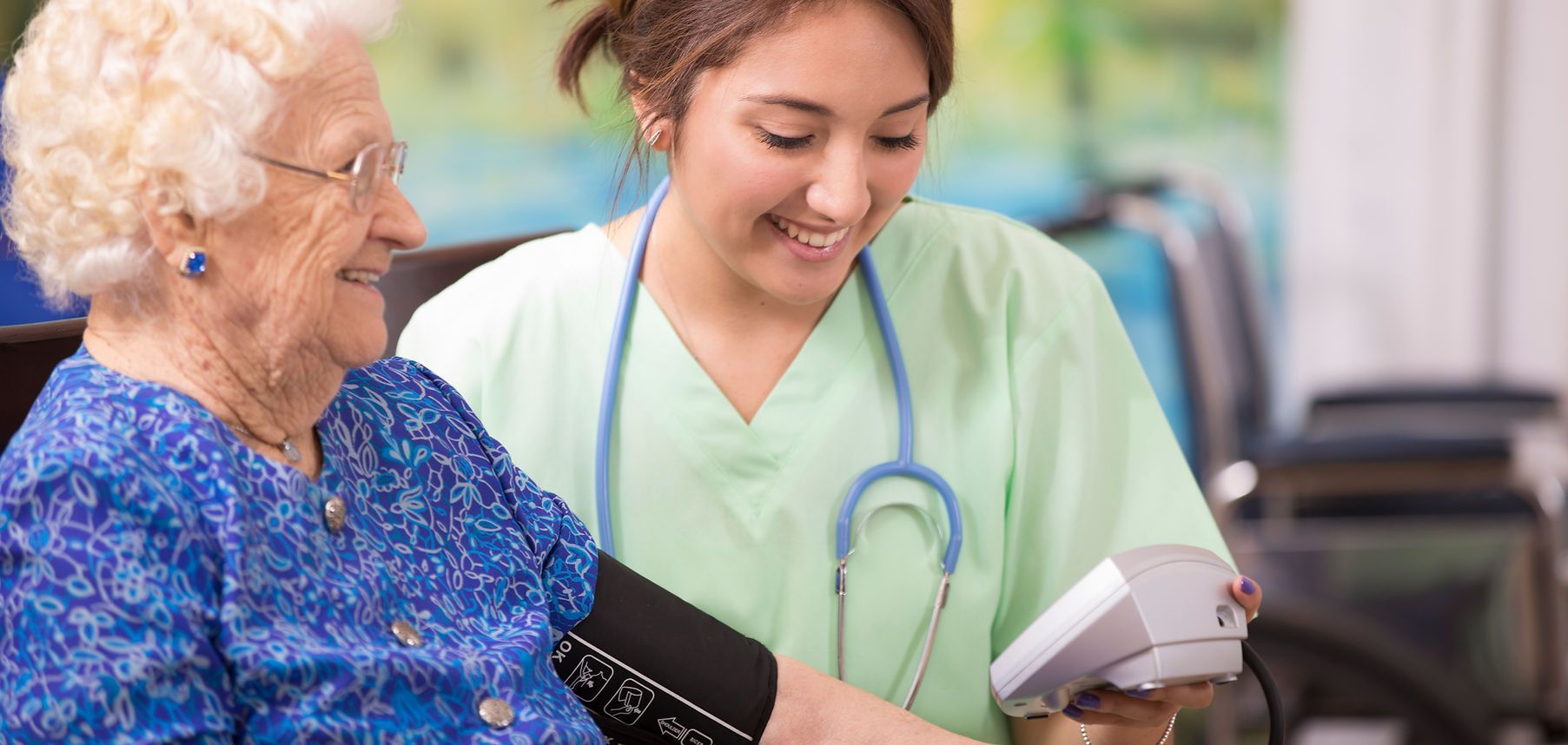 Nurse taking blood pressure of a smiling patient in a clinic waiting area