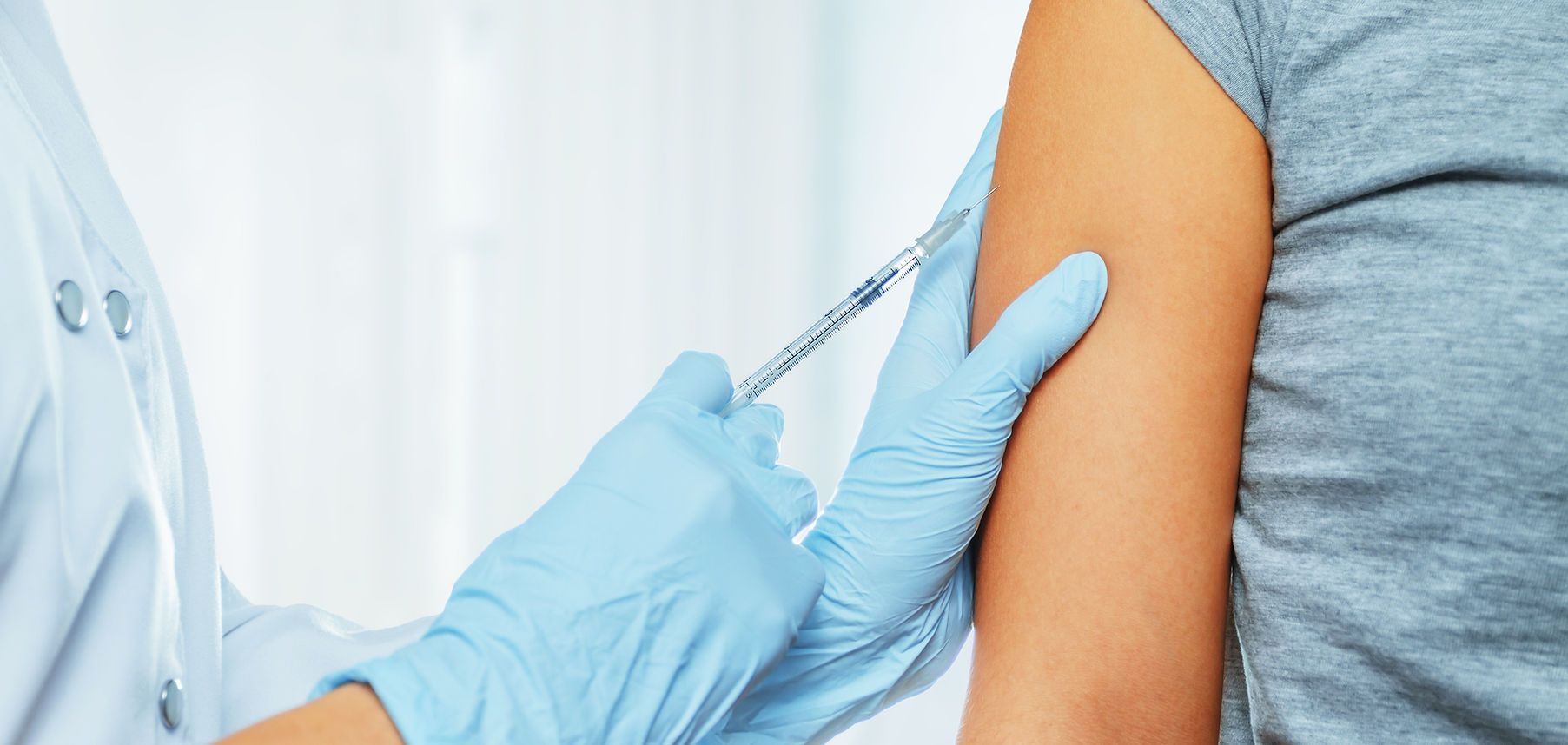 Healthcare worker giving a vaccine injection in a person’s upper arm