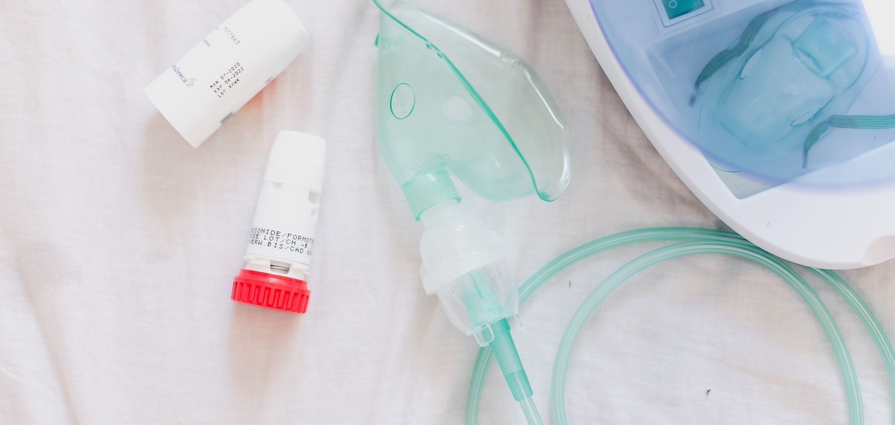 Two small tubes and a green-tinted oxygen mask on a light background