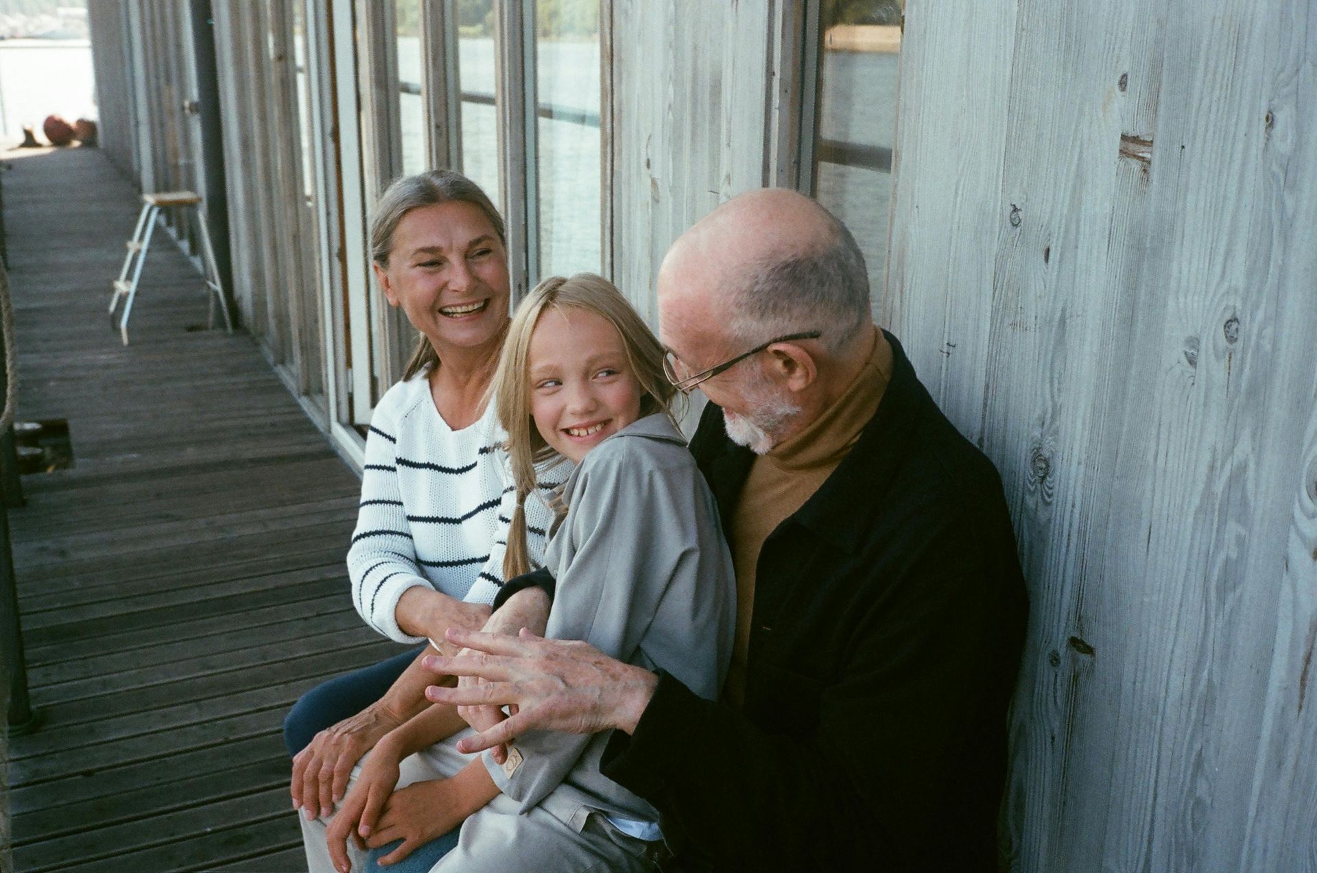 A man and woman are sitting on a porch with a little girl.