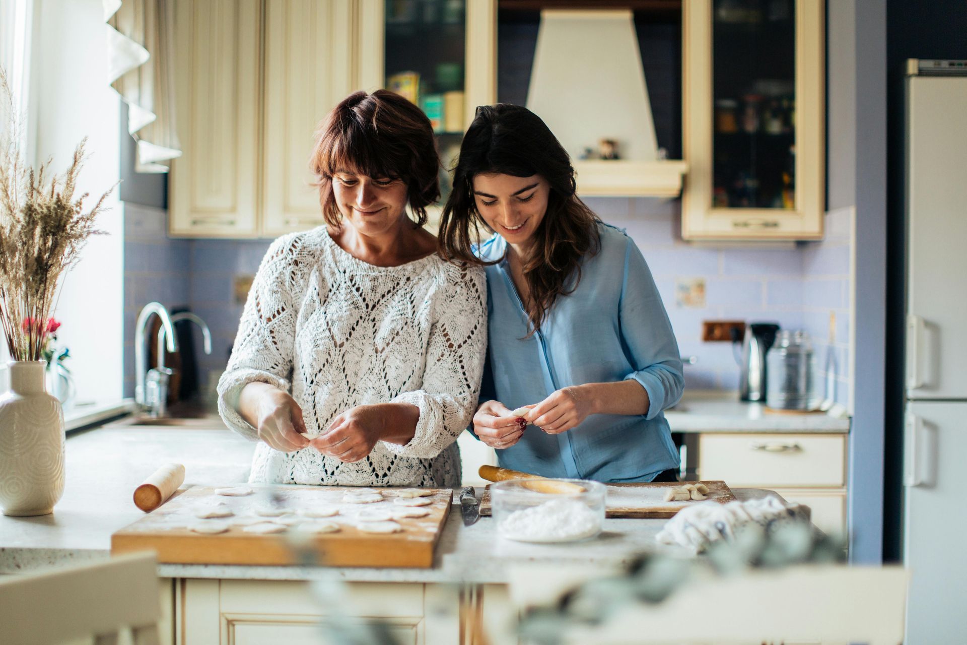Two women are standing in a kitchen preparing food.