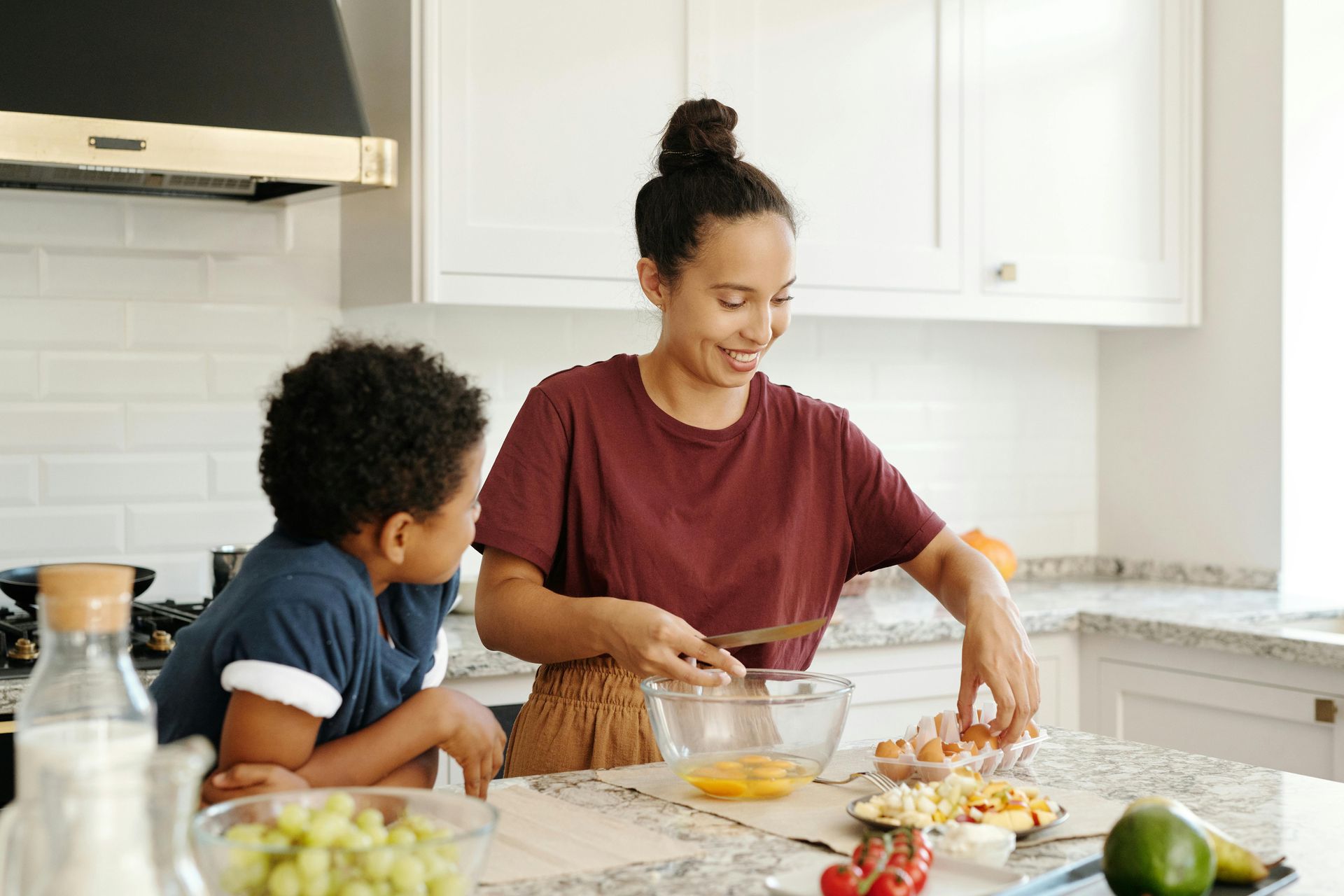 A woman and a boy are preparing food in a kitchen.