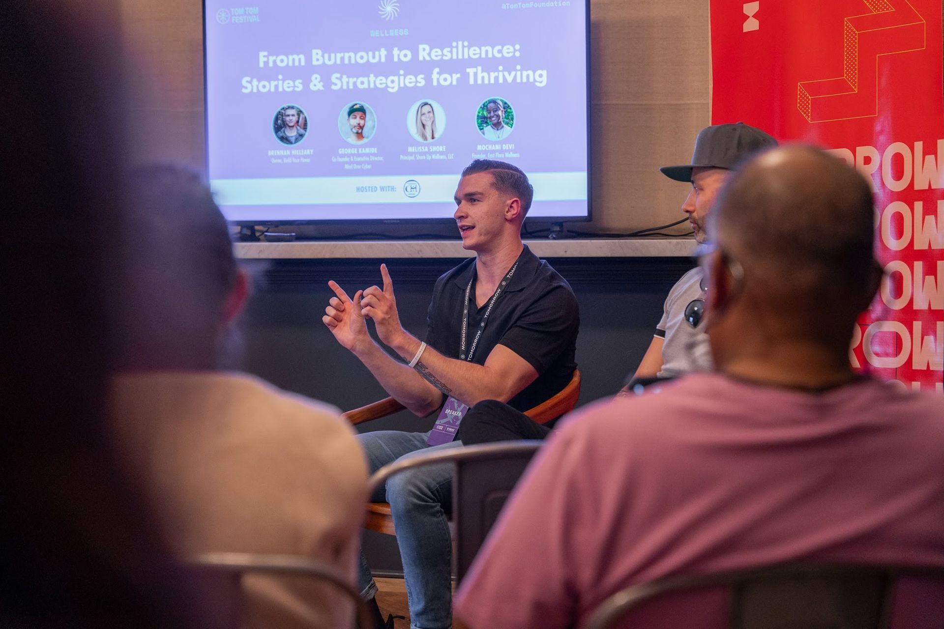 Panel discussion: Man speaking, gesturing, at event. Title on screen: 