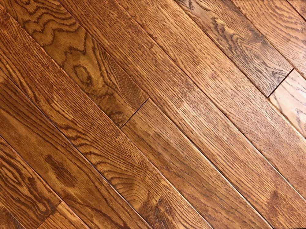 Angled view of a warm-toned hardwood floor with visible wood grain.