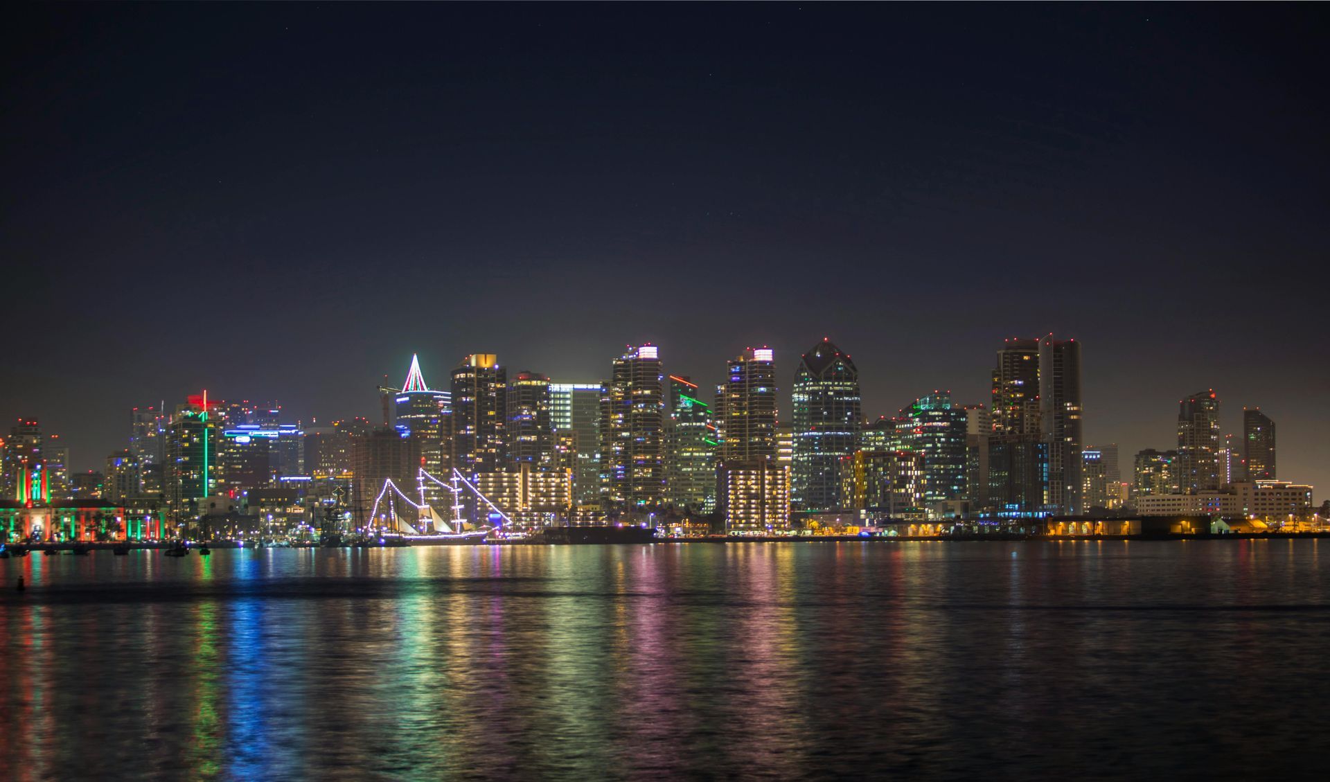 City skyline at night with colorful lights reflecting on calm water