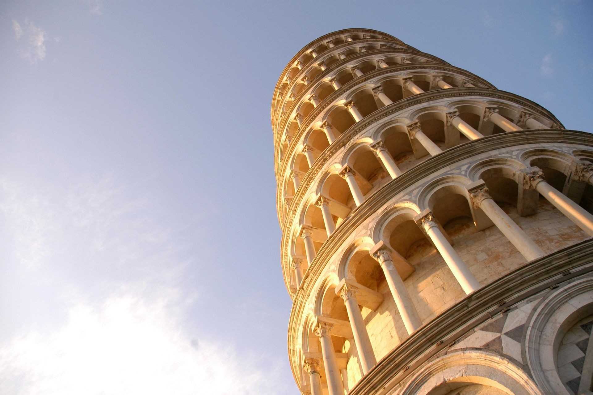 Leaning Tower of Pisa viewed from below against a pale blue sky
