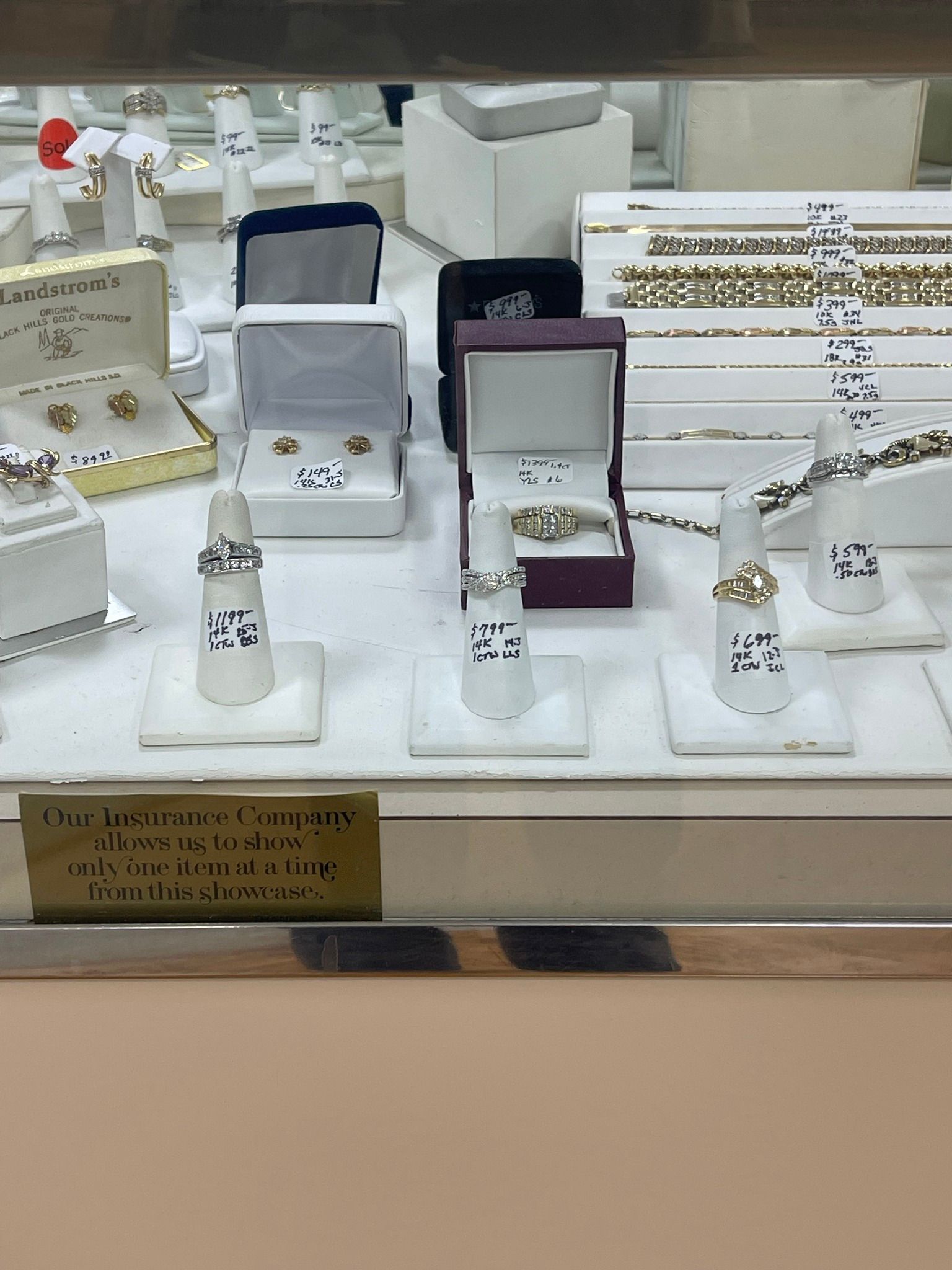 Jewelry store display with diamond rings in white and purple velvet boxes on a glass counter
