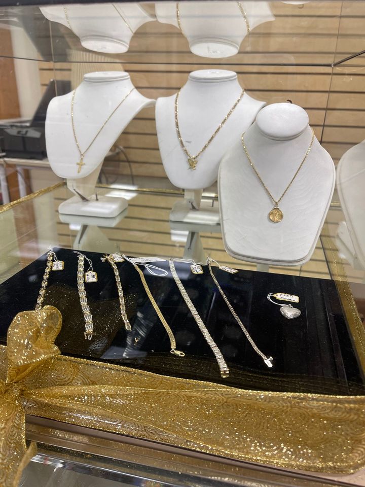 Jewelry display with white necklace busts and gold necklaces above black and gold trays