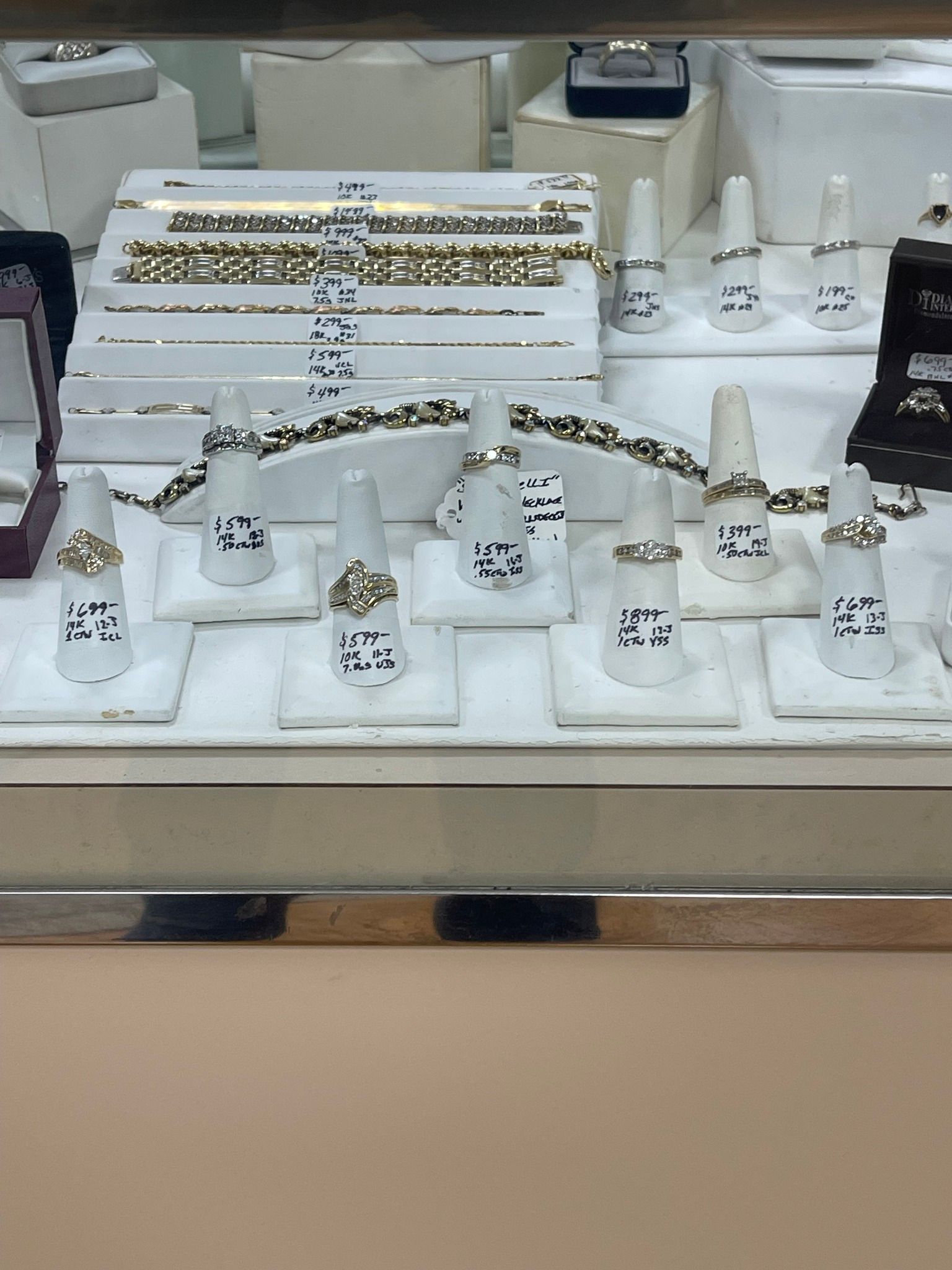 Jewelry display case with rings and bracelets arranged on white stands in a store.