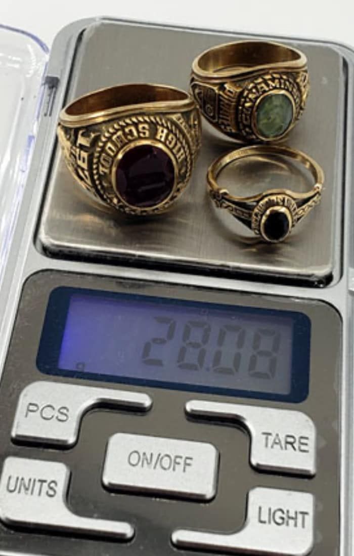 Three gold rings on a digital scale, weighing 28.08 grams