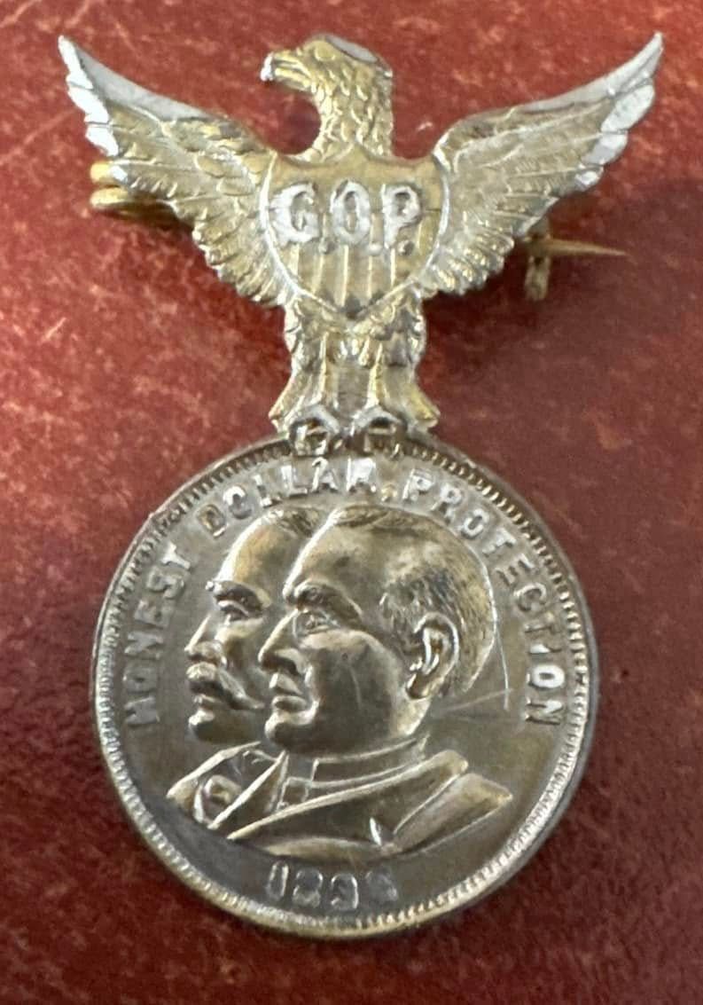 Silver winged medal with a Soviet-style eagle and two profile portraits on a red background