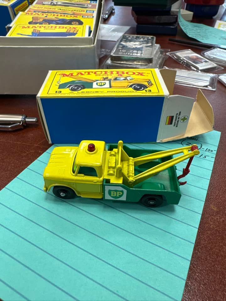 Yellow-and-green toy tow truck on a desk beside its open box and packaging.