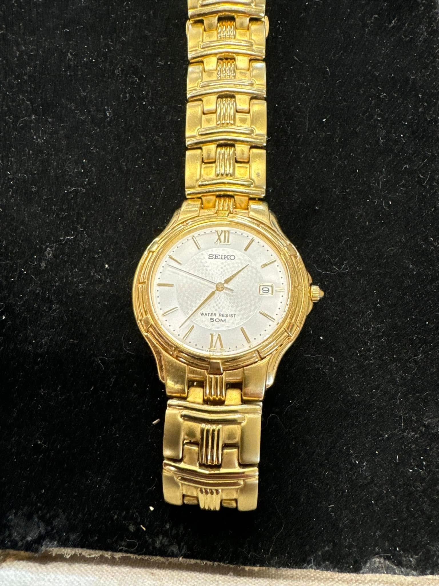 Gold wristwatch with a white dial on a black background
