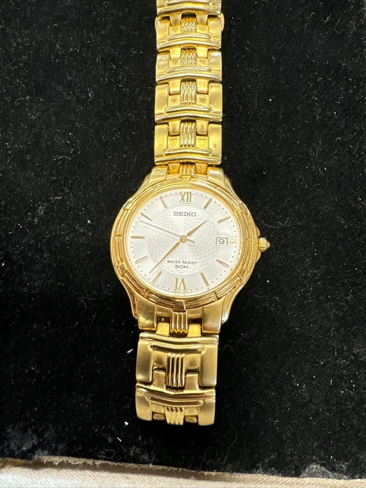 Gold wristwatch with a white dial on a black background