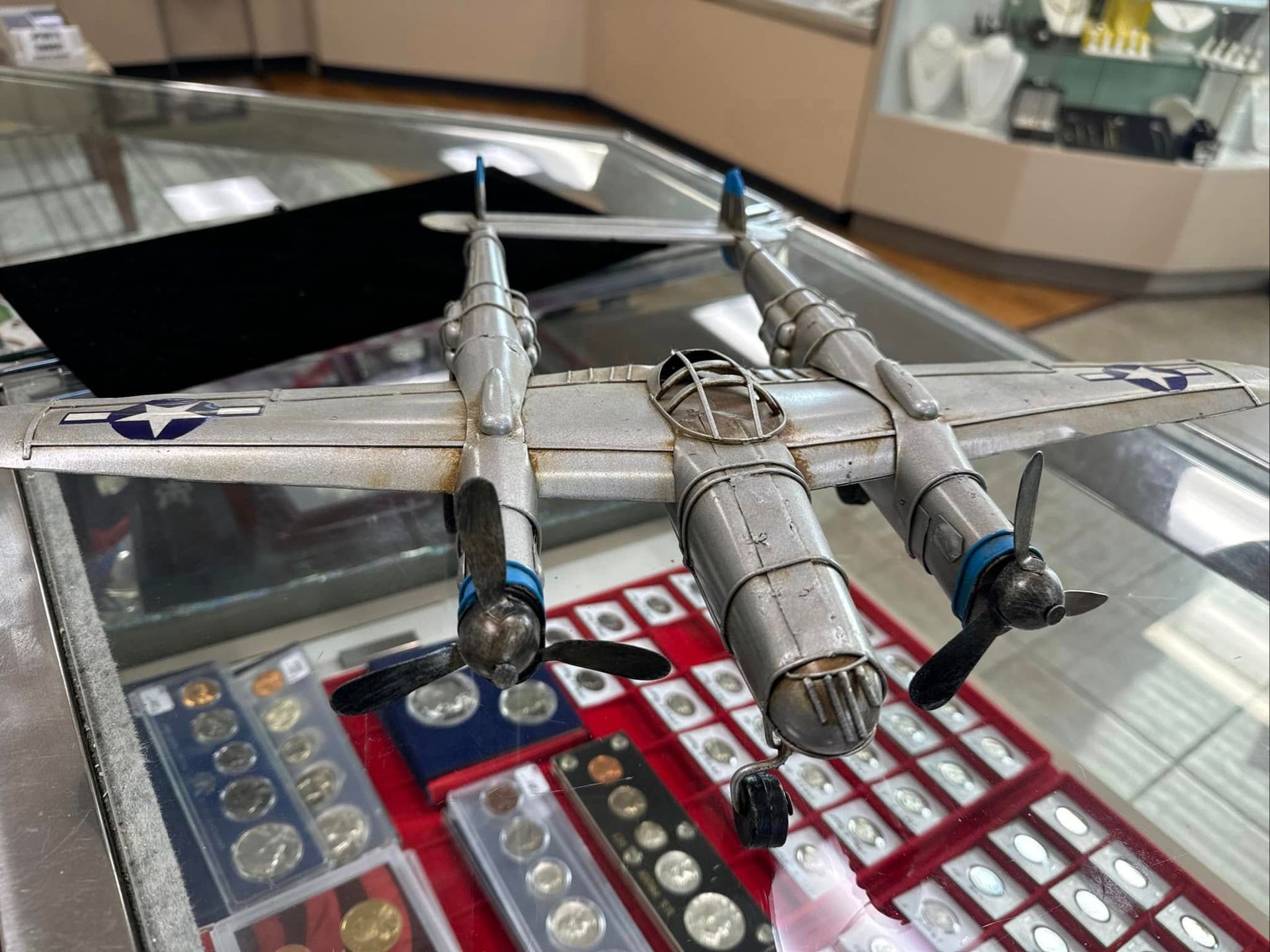 Model twin-engine airplane display on a glass case with trays of collectible pins underneath
