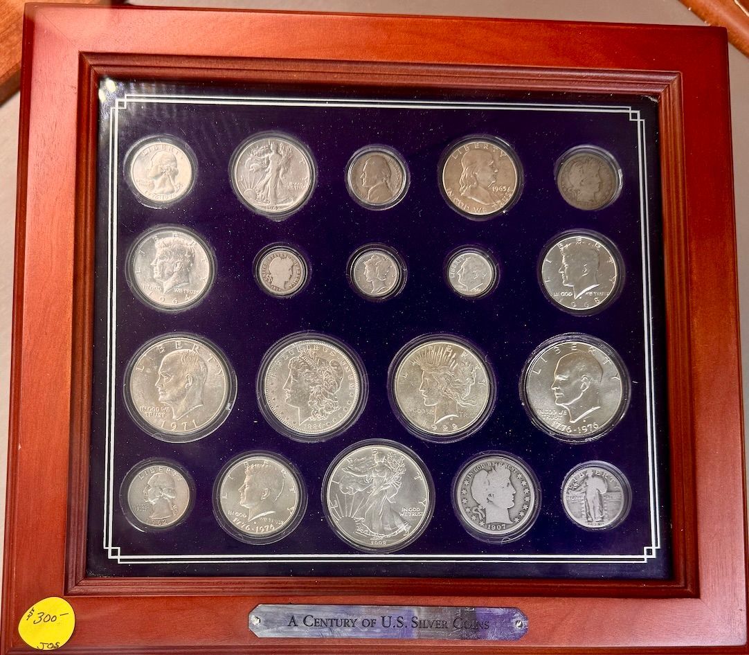 Framed display of silver coins arranged on a dark blue background in a wooden case