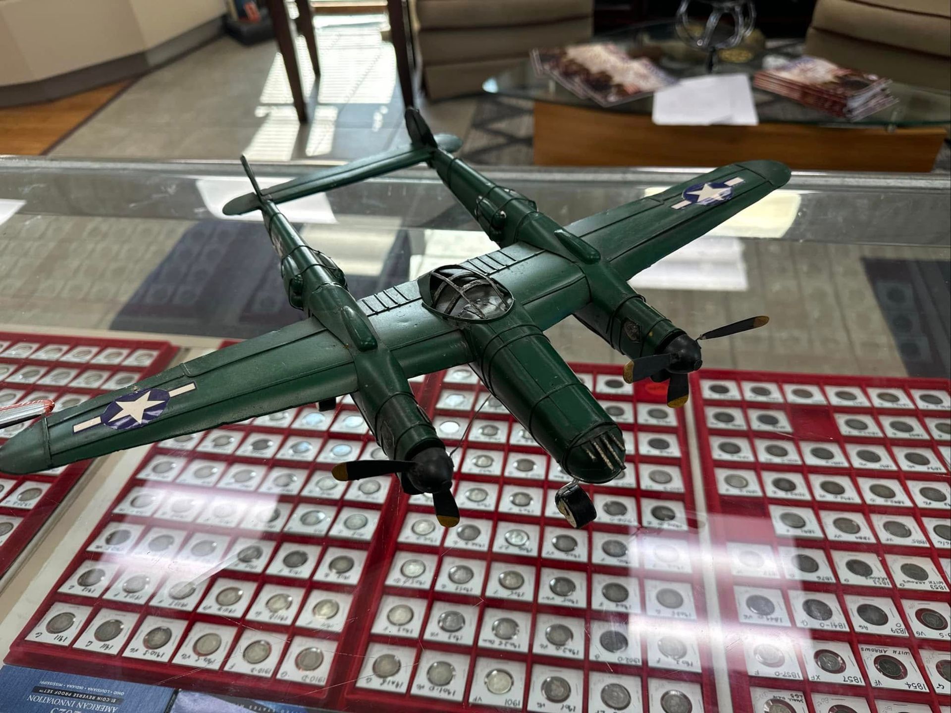 Green model airplane on a glass table with red-and-white cards beneath it