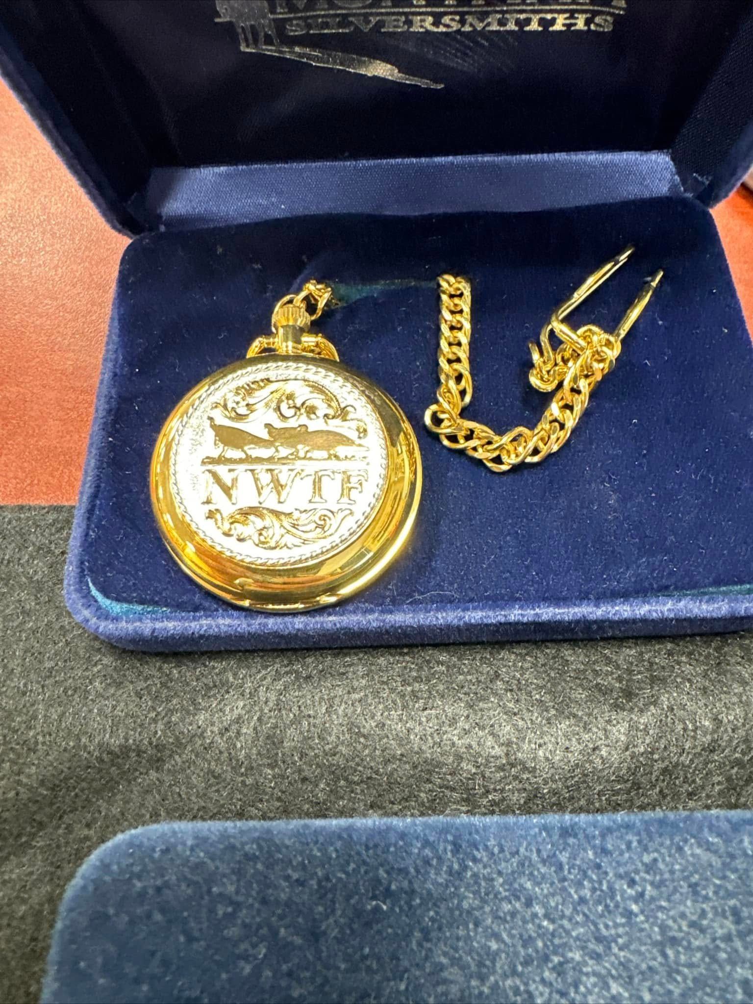 Gold pocket watch and chain in an open blue velvet box with a matching case