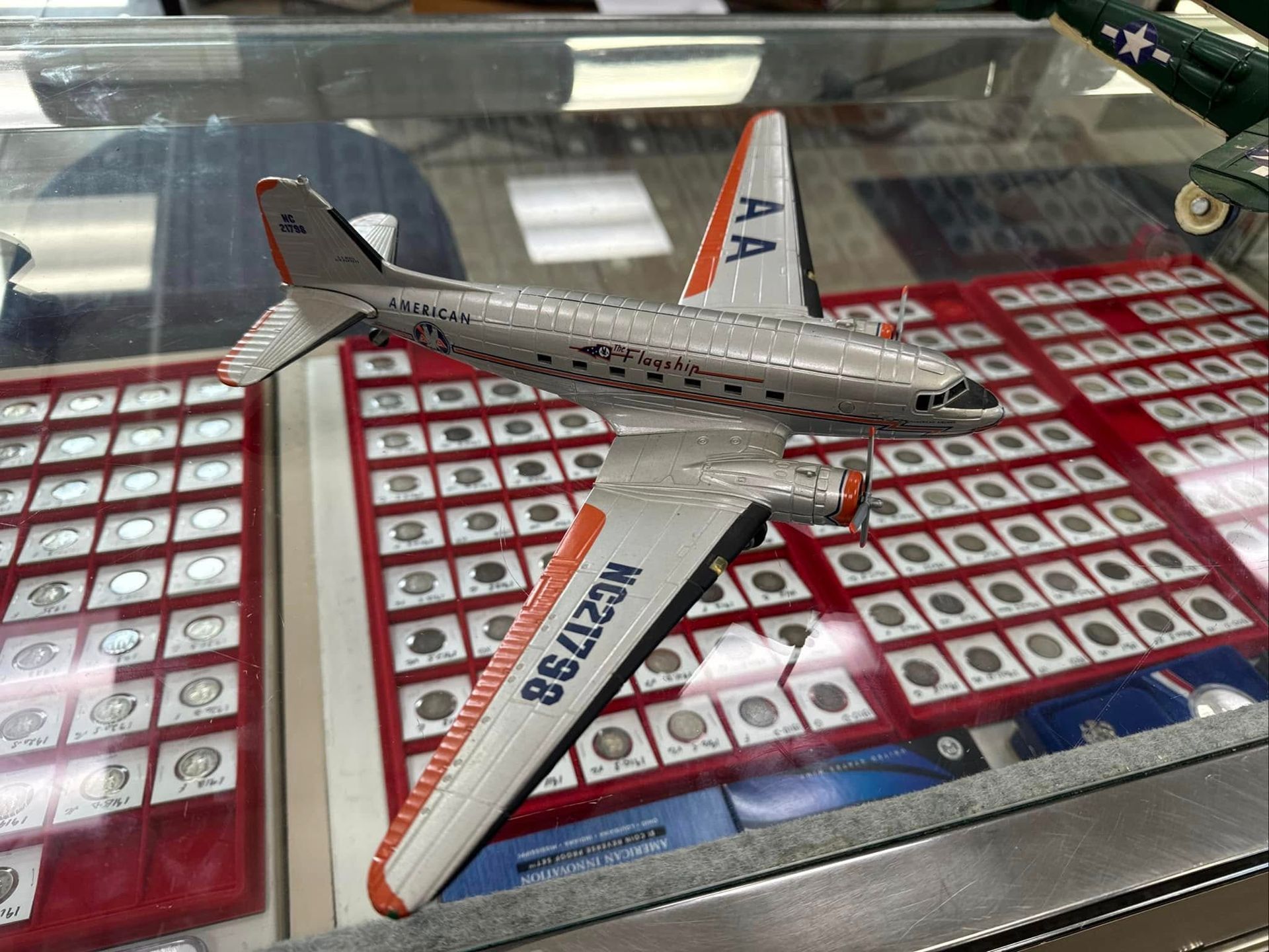 Silver model airplane on a red patterned display shelf, viewed from above.