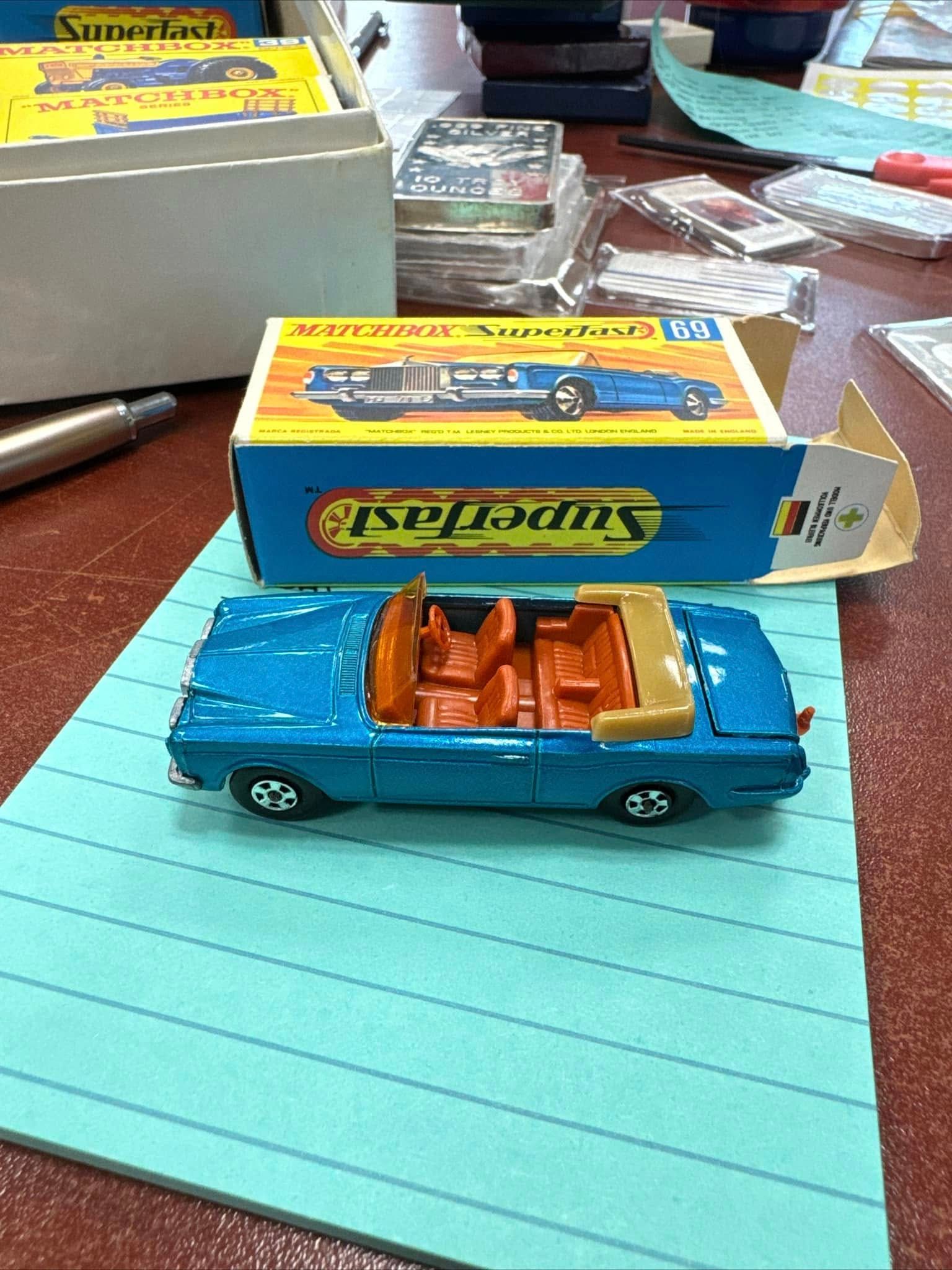 Blue toy convertible car on lined paper with its box and other toy packages in the background