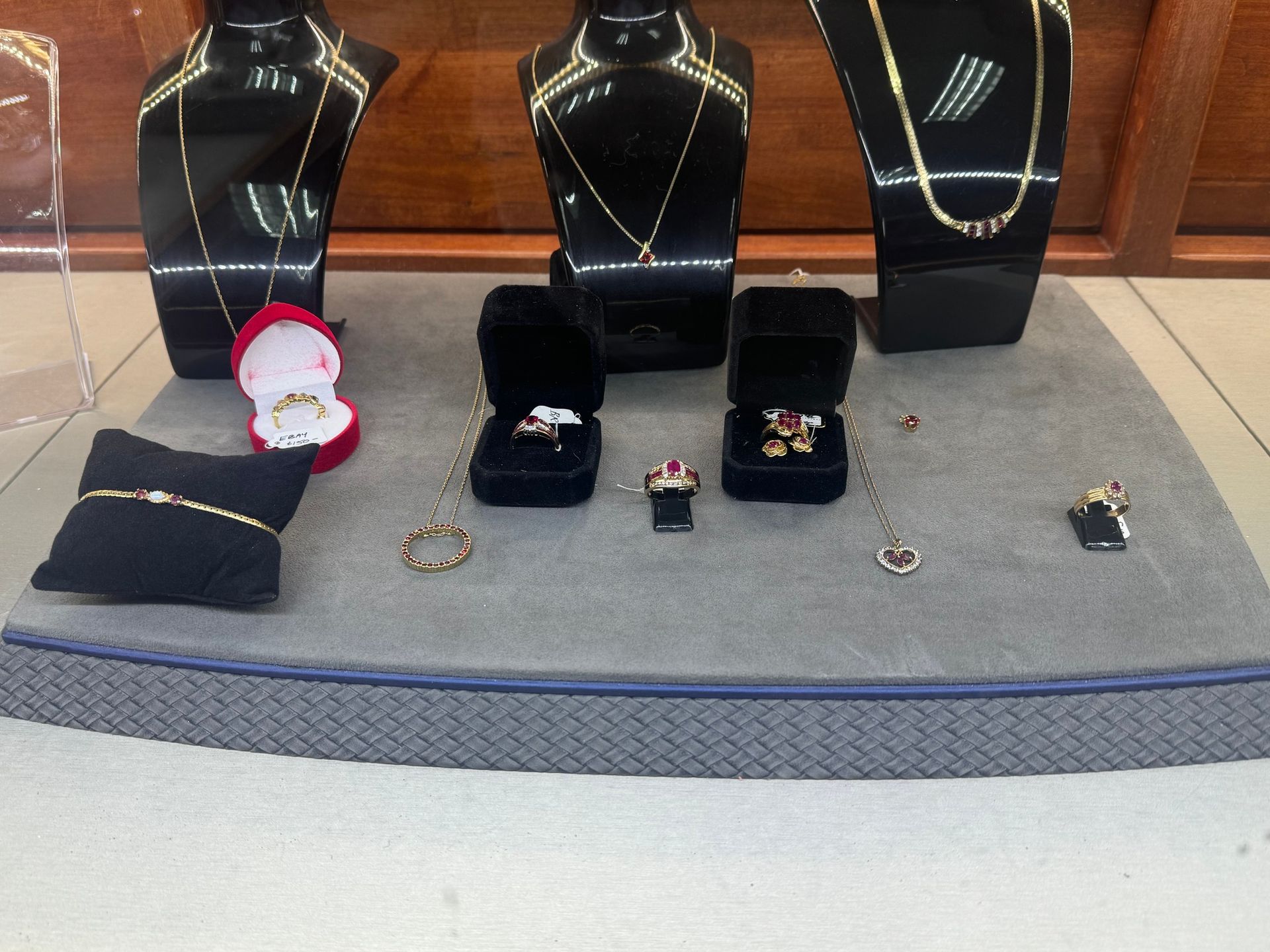 Jewelry display with black necklace busts, rings, bracelets, and earring stands on a gray table.