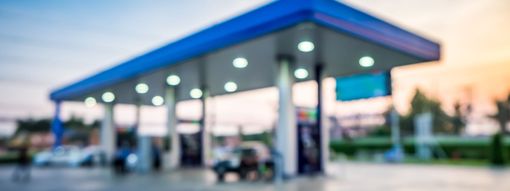Gas station canopy at dusk with blue roof lights and several fuel pumps.