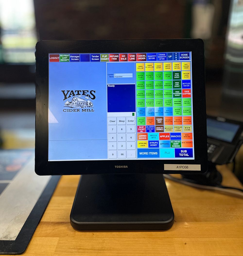 Restaurant POS touchscreen on a wooden counter with a colorful order grid and Yates logo.